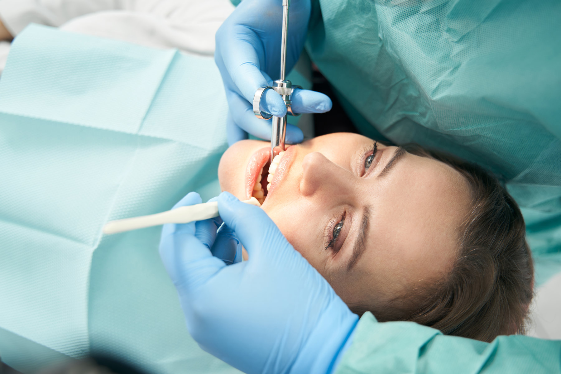 Close up of dentist hands in sterile gloves doing local anesthesia injection before dental procedure in stomatology clinic