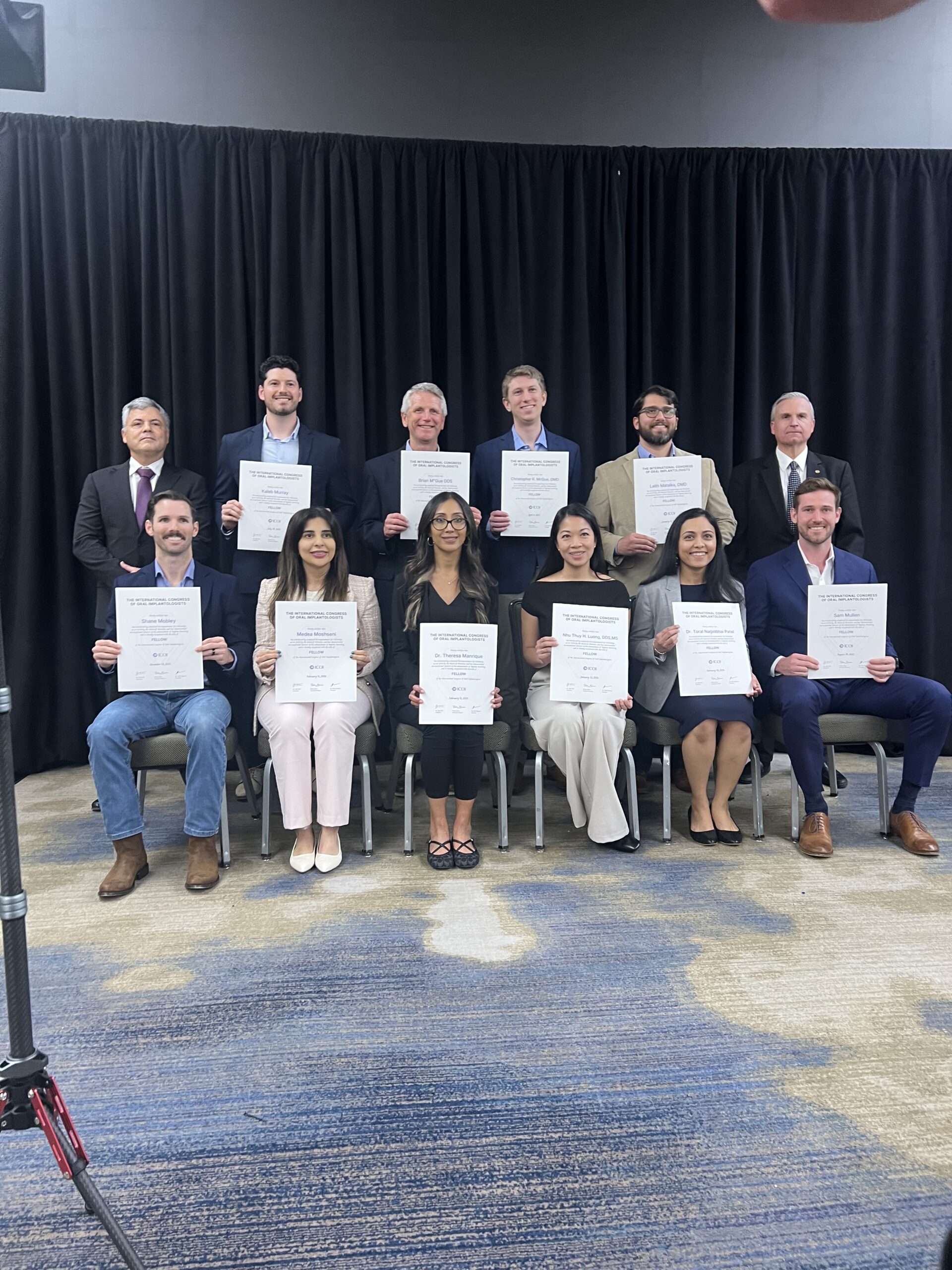 Group of 11 dental professionals holding certificates at implantology conference