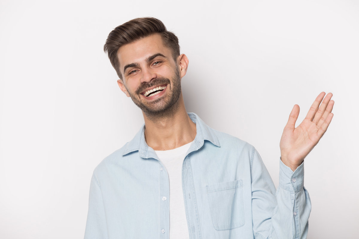 Close up head shot portrait handsome man showing high five gesture. Happy client waving hand in greeting gesture and looking at camera, giving high five to friend, isolated on gray studio background.