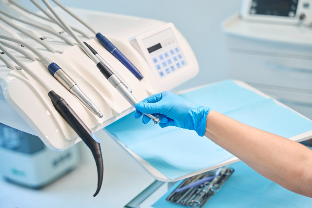 Dentist at his workplace in a dental office, there is a lot of modern equipment in the room